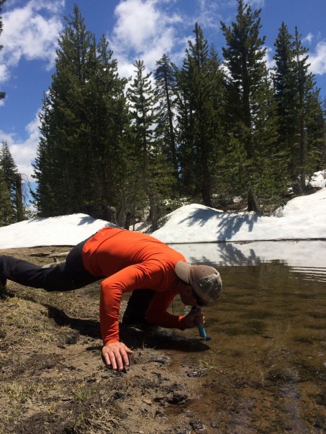 mick pearson drinking out of a muddy pond with the lifestraw...