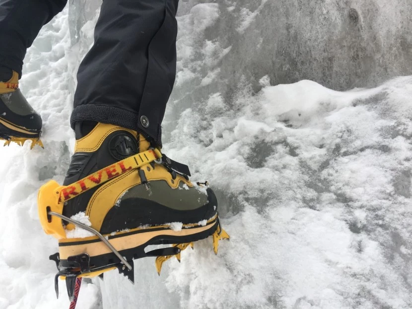 Female mountaineer wearing technical boots with crampons on ice climbing route