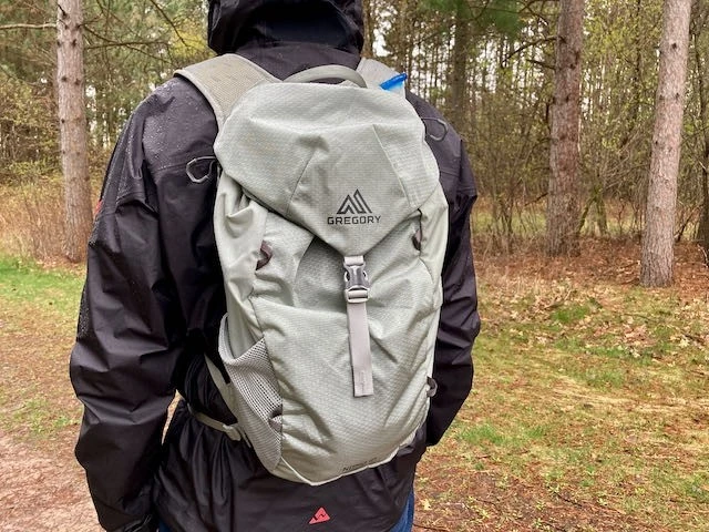 Hiker using water bag for hiking on mountain trail with hydration tube