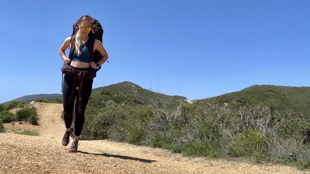 Young person hiking female standing on top rock, Backpack woman