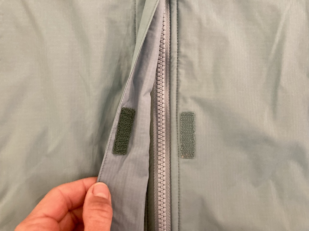 budget rain jacket womens - the rei rainier has a velcro storm flap to cover the zipper.