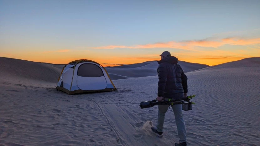 Camping tent setup in wilderness with sleeping gear laid out nearby