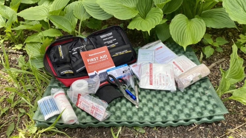 First aid kit and safety equipment laid out on camping table