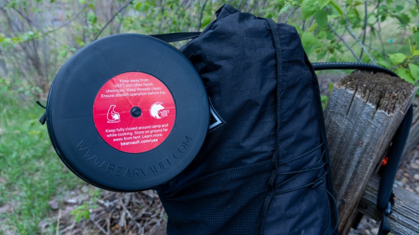 a bear canister can be fitted to the top of the bag's roll top using...