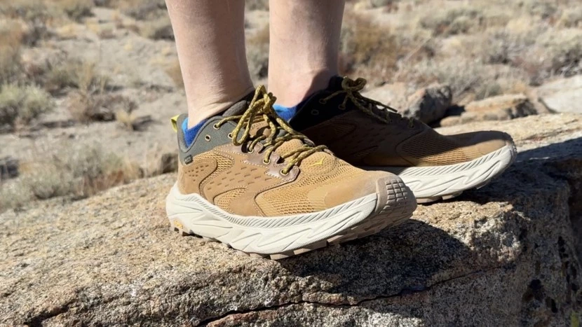 Hiker wearing best hiking shoes on mountain trail with scenic peaks in background