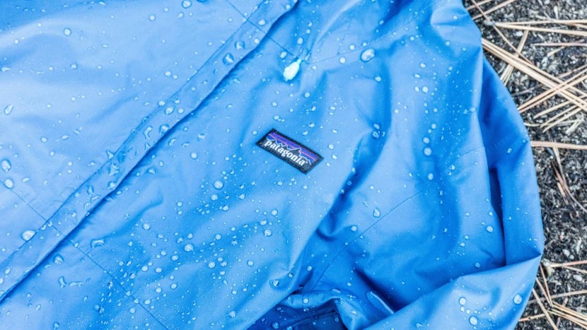Testing rain jackets in heavy downpour conditions with water streaming off jacket