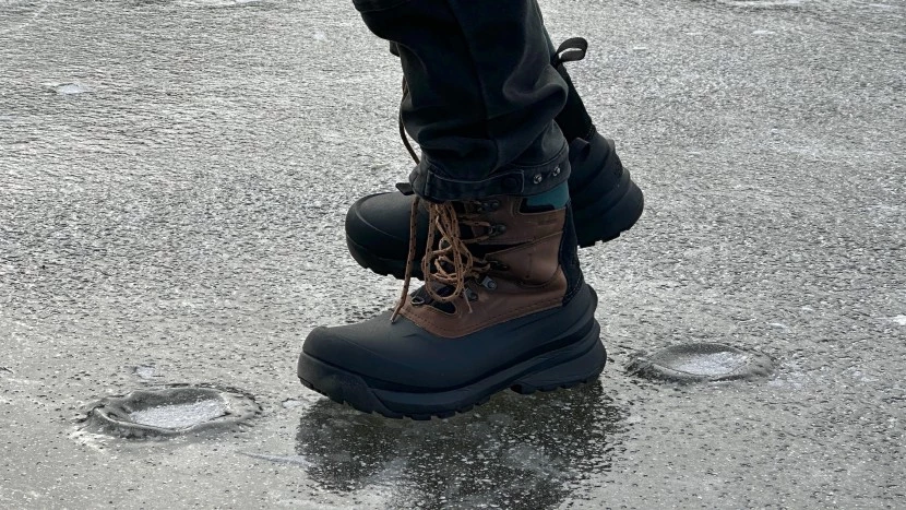 Person wearing comfortable waterproof winter boots while walking on icy trail, demonstrating proper traction and warmth in snowy conditions