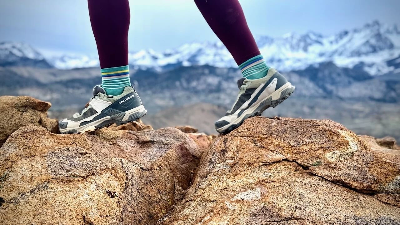 Woman hiking on mountain trail wearing proper hiking shoes with scenic valley view